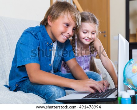 Portrait of smiling children burying in notebook and busy with game
 Royalty-Free Stock Photo #491478994