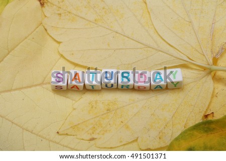 Word Saturday posted from small multi-colored letters on a background of autumn leaves / Weekdays word series