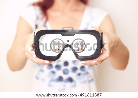 Close-up image of woman presenting virtual reality goggles to the viewer