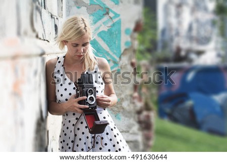 Horizontal shot of a blonde woman in dotted dress holding a medium format photography camera