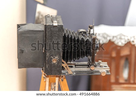 Old retro camera standing on a wooden tripod closeup