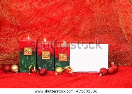 Holiday candles, blank white sign, and red and gold ornaments with royal red and golden sparkle linen background; Christmas and spiritual background with white copy space
