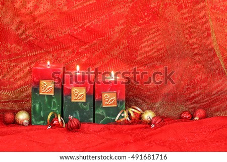 Holiday candles and red and gold ornaments with royal red and golden sparkle linen background; Christmas and spiritual background with red copy space