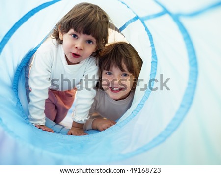 two 2-3 years old girls peeking from blue toy tunnel. Horizontal shape, Copy space Royalty-Free Stock Photo #49168723