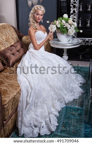 Young blonde woman in wedding dress in the interior