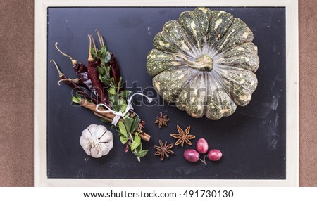 Halloween pumpkin and garlic, chili peppers, aniseed on chalkboard background flat lay