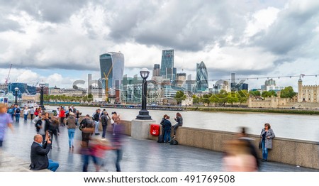 Blurred image of tourists walking along river Thames in London, UK.
