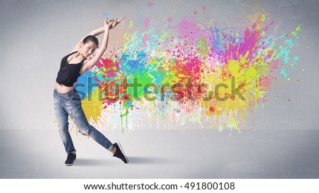 A funky contemporary hip hop dancer dancing in front of grey background with colorful bright paint splatter concept