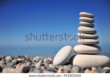 Stones pyramid with a blue sky and sea horizon on background, summer beach scene