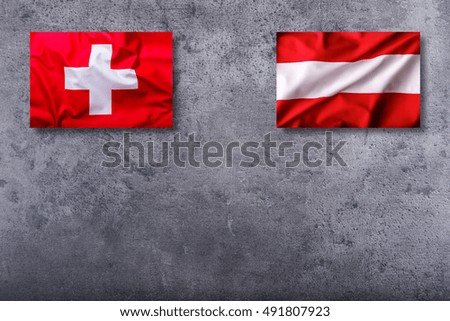 Flags of the switzerland and austria on concrete background.