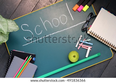 Crayons, apple and notebook on blackboard