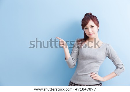 beauty girl student show something and smile to you with isolated on blue background, asian
