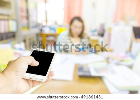 Man use mobile phone, blur image of inside office as background.
