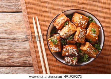 Traditional fried tofu with sesame seeds in a bowl macro. horizontal view from above
