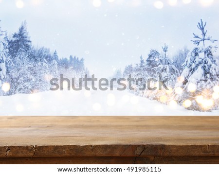 Empty wooden table in front of dreamy and magical winter landscape background. For product display montage