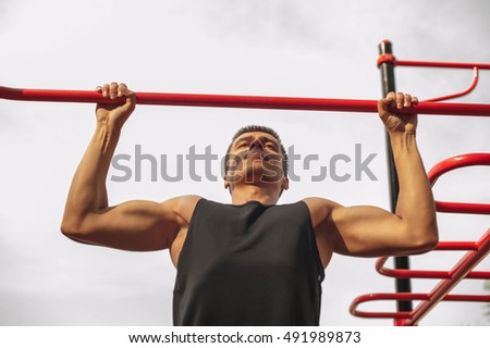 strong young guy performing exercises on the bar and squeezed