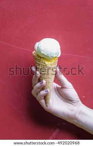 ice cream in waffle cup in female hand on red background