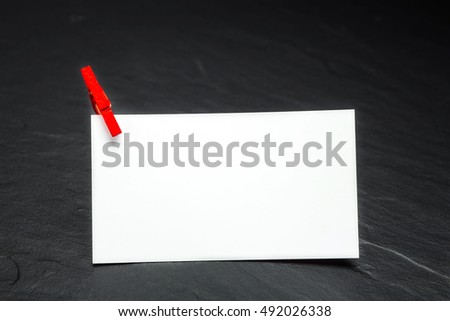 close up of a note paper and clothes pegs on a black background