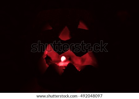 Scary Halloween pumpkin isolated on a black background. Red colored scary glowing face.