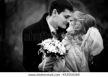 Black and white picture of groom leaning to bride for a kiss holding her shoulders tender