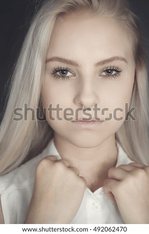 Alternative young female model with blonde hair and piercings in her nose on a dark background. teenage girl. fashion concept.