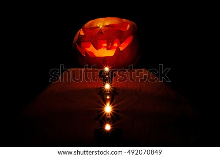Halloween pumpkin on the altar with candles leading to it, the dark, front view