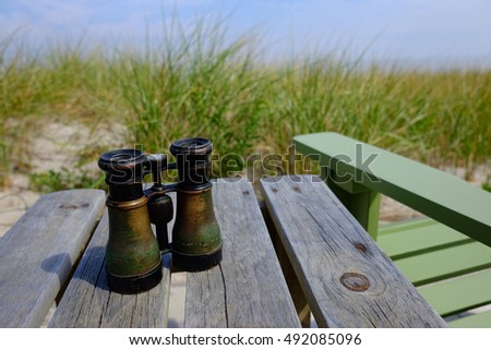 A Pair of Vintage Binoculars sitting on Wooden Table at Beach Sea Shore