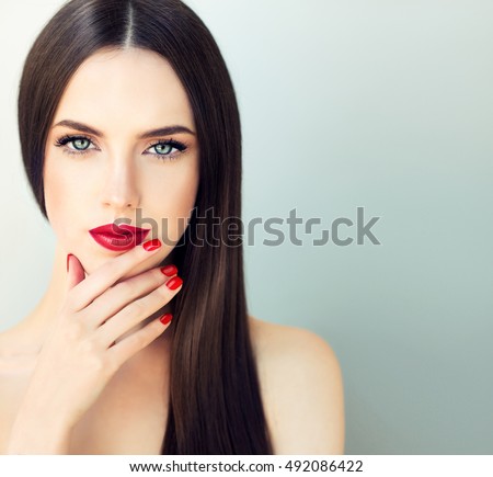 Beautiful  brunette model girl with  long shine  hair .  Red lips and nails manicure .