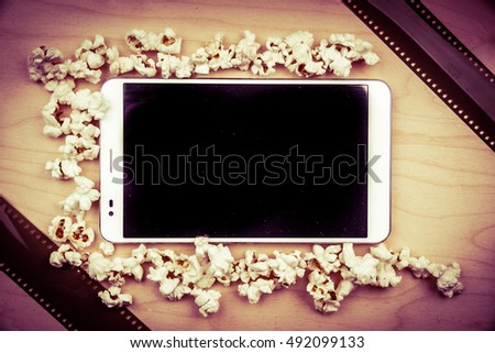 Tablet pc on wood with attributes of cinema. Visual metaphor for internet content - films and media on a mobile device.