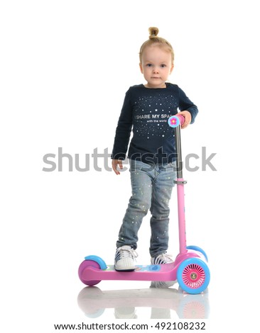 Little child toddler girl learning to ride and balance on push three Wheel Adjustable Height Scooter isolated on a white background