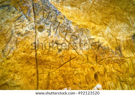 Orange, Sandstone Cave Wall with Carved, Graffiti Initials and Water Erosion.