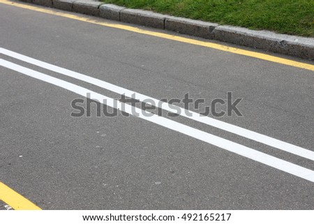 Two white parallel lines on asphalt background