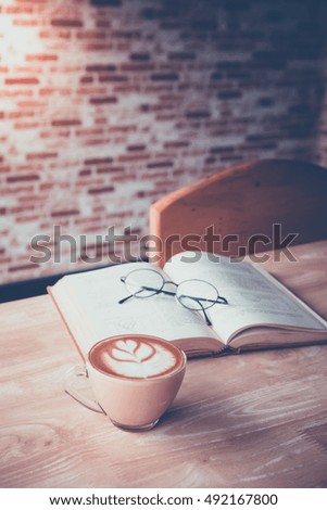 A cup of coffee on wood table with text book and glasses. retro picture style