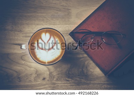 Coffee latte art on wood table with glasses on  old book,retro picture style