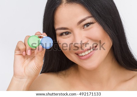 Picture of happy Korean or Asian woman demonstrating container for contact lenses isolated on white background in studio.