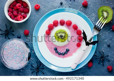One eye panna cotta with kiwi fresh berries and sauce, Halloween recipe. Creative idea for kids dessert on holiday party top view