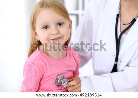 Pediatrician is taking care of baby in hospital. Little girl is being examine by doctor by stethoscope. Health care, insurance and help concept.