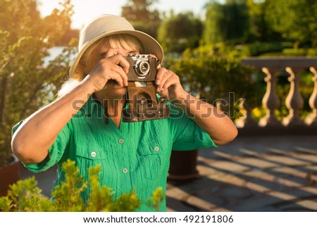 Mature woman holding camera. Lady in summer hat. What a wonderful view. Few photos of nature.