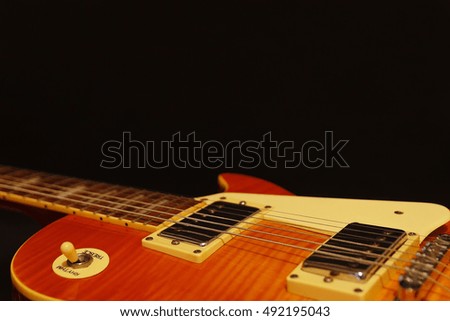 Honey sunburst vintage electric jazz guitar closeup on the black background, with plenty of copy space. Selective focus.