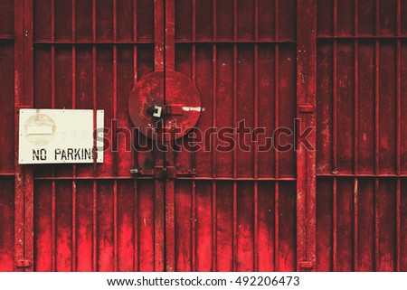 Bright red ply lattice door with padlocks and white sign prohibiting parking, the concept of reliability, Security, Protected