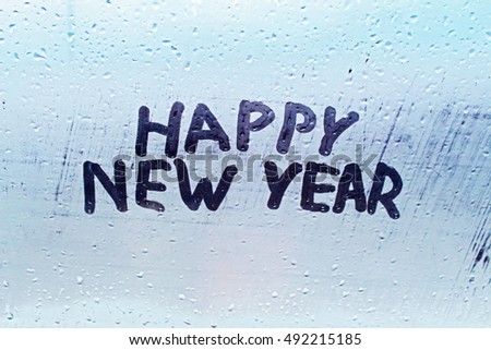 The inscription "happy new year" on the misted window