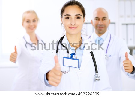 Happy doctor woman  with medical staff at the hospital. Thumbs up and Ok sign!