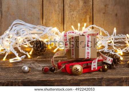 One handmade gift box on sledge with christmas lights on wooden background
