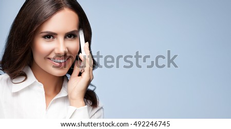 Businesswomen or customer support phone operator with cell phone, blank copyspace area for advertising slogan or text message. Caucasian brunette model in help servise and client consulting shoot. 
