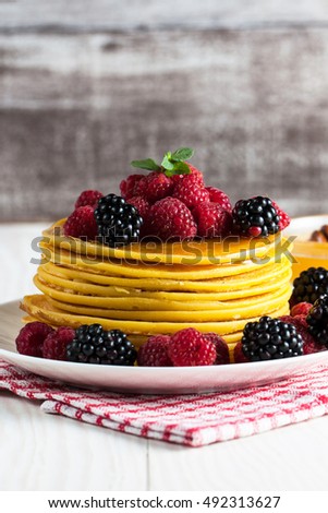 Fresh made delicious pancakes with berries, blackberries, raspberries, banana, honey and maple syrup. Healthy morning breakfast concept.