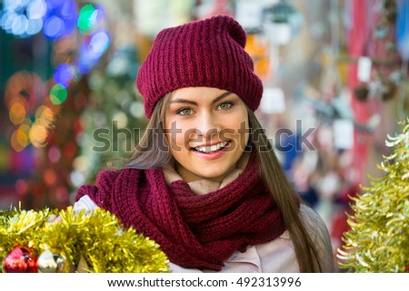 Happy smiling woman choosing Christmas decoration at market