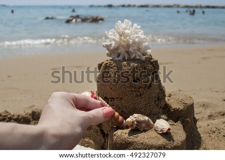 Girl is making a Sandcastle with coral on sandy beach