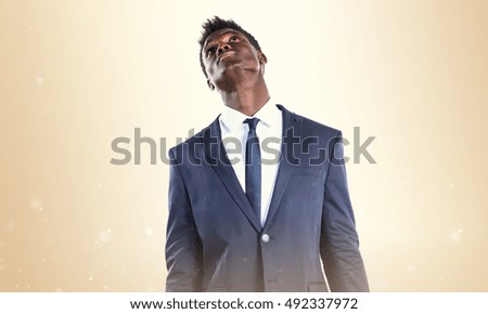 Handsome black man looking up over ocher background