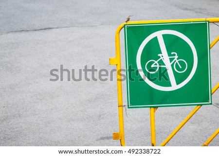 A green and white sign show no bikes are allowed on the path.