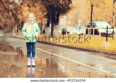 girl jumping in the puddles in the autumn rain